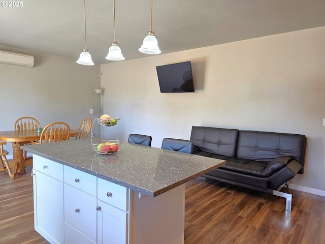 755 Nebraska St, Eugene, OR 97402 - kitchen featuring wood finished floors, a center island, dark stone countertops, white cabinets, and a wall unit AC