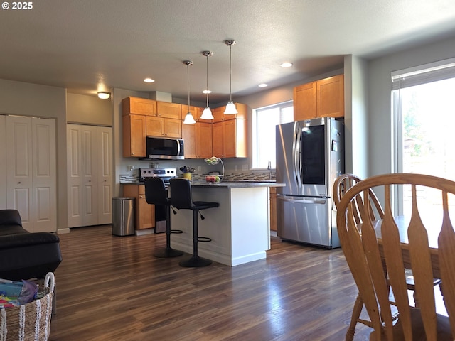 755 Nebraska St, Eugene, OR 97402 - kitchen featuring appliances with stainless steel finishes, dark countertops, dark wood-style floors, a center island, and recessed lighting