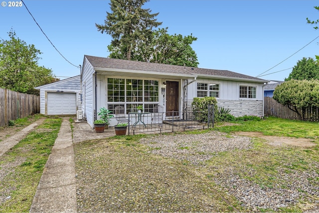 view of front of house featuring concrete driveway, fence, stone siding, and a detached garage
