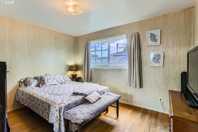 bedroom with baseboards, wood walls, and wood finished floors