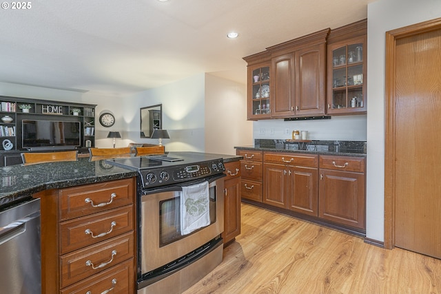 kitchen featuring stainless steel appliances, light hardwood / wood-style floors, and dark stone counters