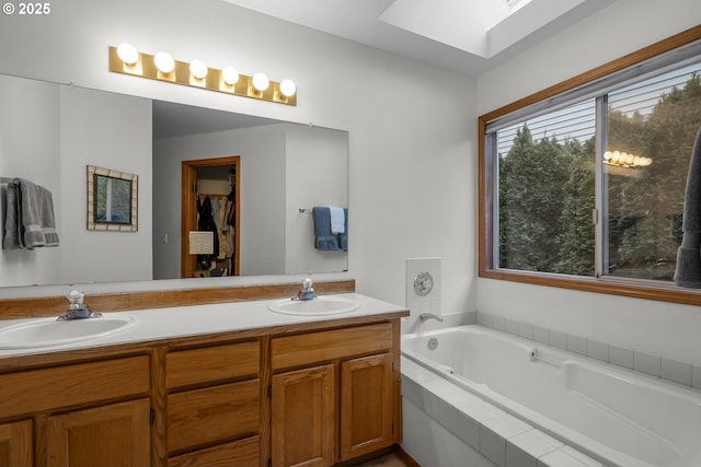 bathroom featuring vanity, tiled bath, and a skylight