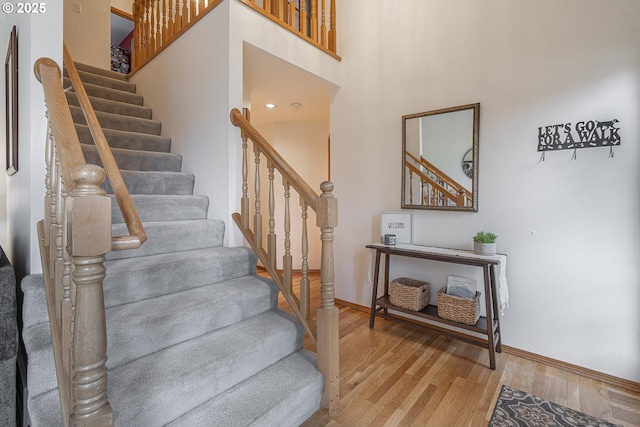 stairs with hardwood / wood-style flooring and a high ceiling