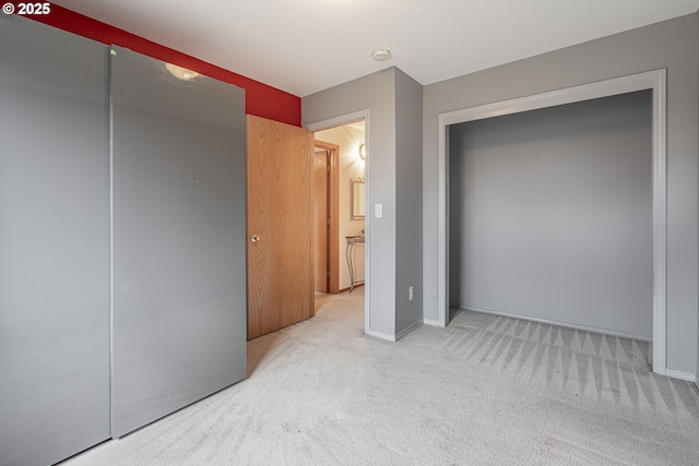 unfurnished bedroom with light colored carpet and a closet