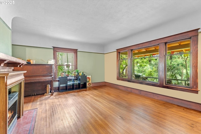 2516 NE Clackamas St, Portland, OR 97232 - living room with a warm lit fireplace, hardwood / wood-style floors, and a textured ceiling