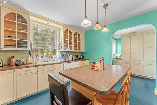 2516 NE Clackamas St, Portland, OR 97232 - kitchen featuring arched walkways, glass insert cabinets, hanging light fixtures, decorative backsplash, and a breakfast bar