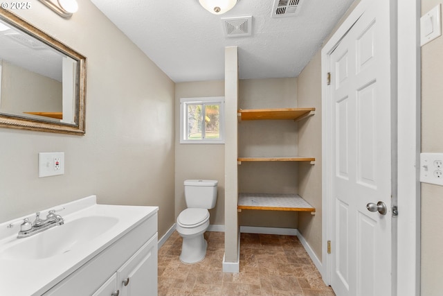 bathroom featuring vanity, a textured ceiling, and toilet