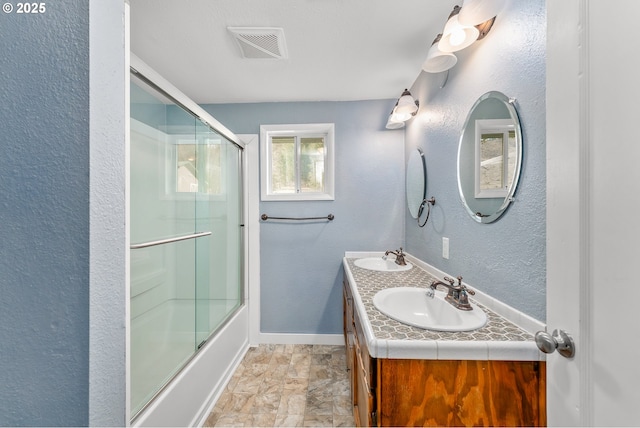 bathroom with vanity and bath / shower combo with glass door