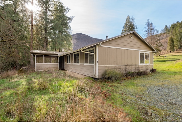 view of side of home featuring a sunroom and a mountain view