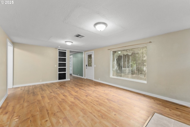 unfurnished room with a textured ceiling and light hardwood / wood-style flooring