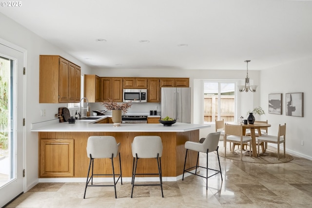 kitchen featuring a wealth of natural light, a sink, stainless steel appliances, a peninsula, and light countertops