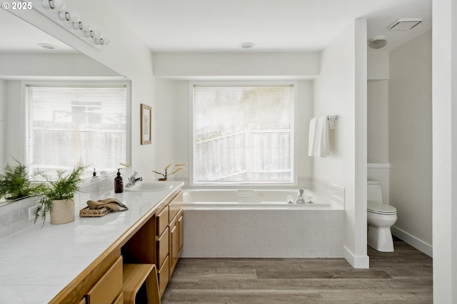 full bathroom featuring vanity, wood finished floors, visible vents, a garden tub, and toilet