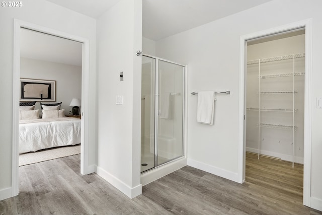 ensuite bathroom featuring a stall shower, baseboards, wood finished floors, and ensuite bathroom