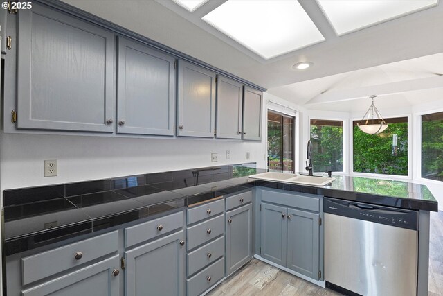 kitchen featuring a sink, dishwasher, a peninsula, light wood-type flooring, and gray cabinetry