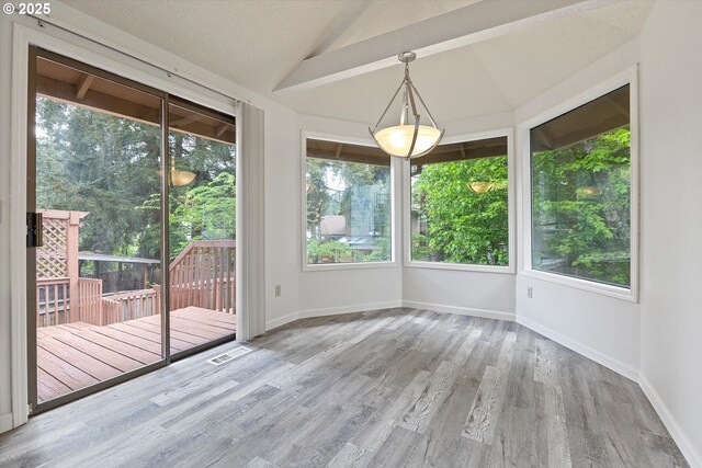 interior space with baseboards, lofted ceiling, wood finished floors, and visible vents