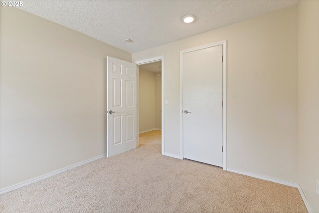 unfurnished bedroom with carpet flooring, a textured ceiling, and baseboards