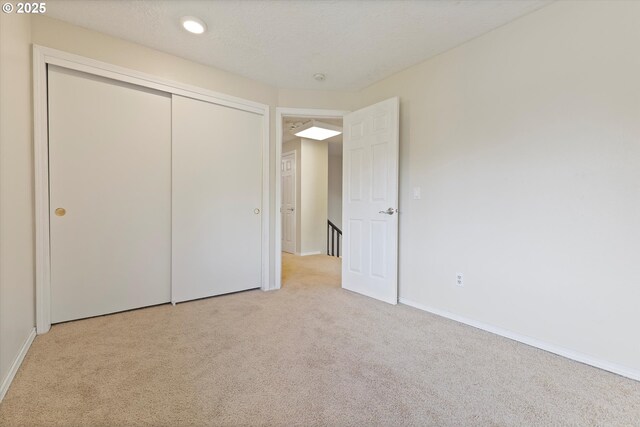 unfurnished bedroom with carpet floors, baseboards, and a closet