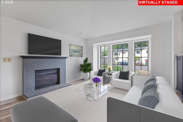 living area featuring baseboards, a textured ceiling, a brick fireplace, and wood finished floors