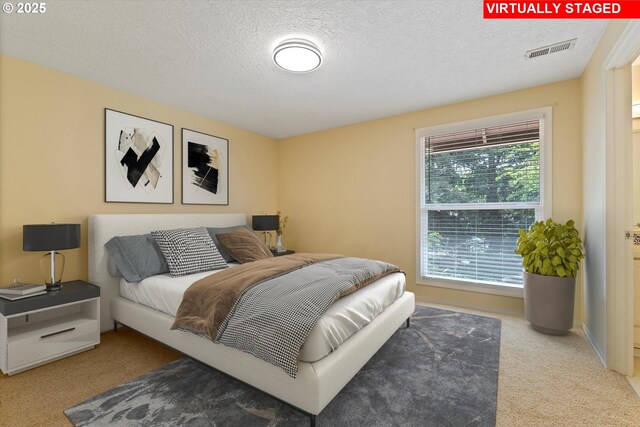 bedroom featuring carpet floors, a textured ceiling, and visible vents