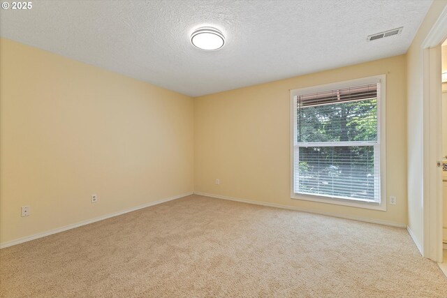 carpeted spare room with visible vents, a textured ceiling, and baseboards