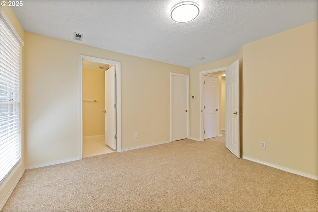 unfurnished bedroom featuring carpet floors, a textured ceiling, baseboards, and connected bathroom