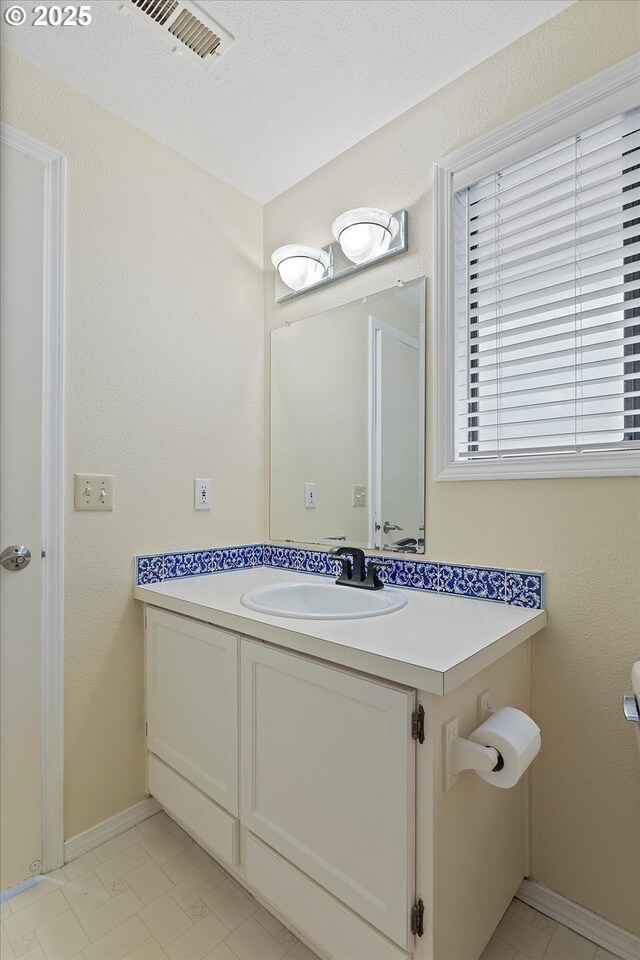 bathroom featuring visible vents, baseboards, and vanity
