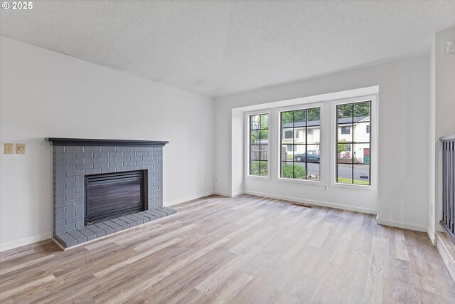 unfurnished living room with a textured ceiling, baseboards, wood finished floors, and a fireplace