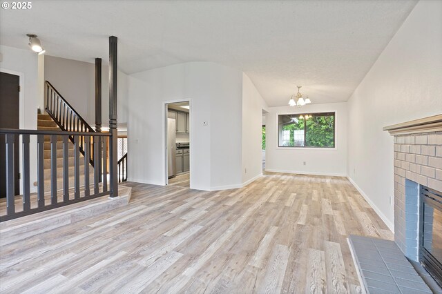 unfurnished living room featuring light wood-style floors, a chandelier, and lofted ceiling