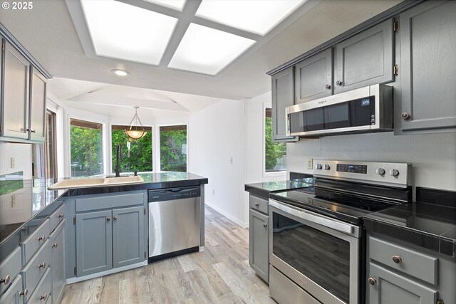 kitchen featuring appliances with stainless steel finishes, a sink, light wood-style flooring, a peninsula, and recessed lighting