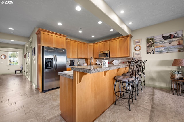 12 NW 17th Pl, Warrenton, OR 97146 - kitchen featuring stainless steel appliances, a peninsula, recessed lighting, a kitchen breakfast bar, and backsplash
