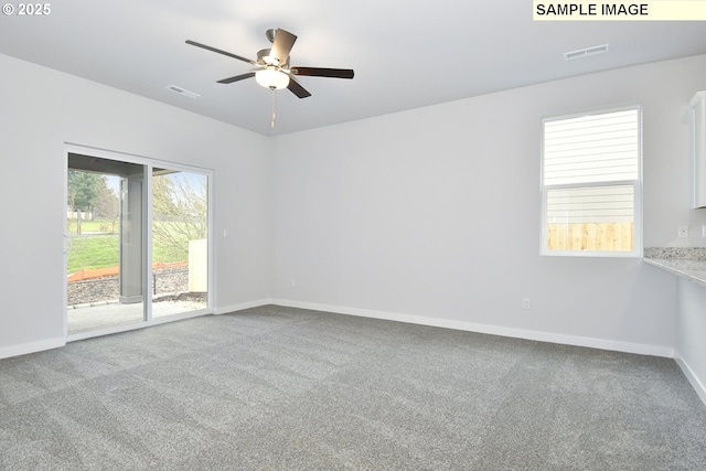 carpeted spare room featuring baseboards, visible vents, and ceiling fan