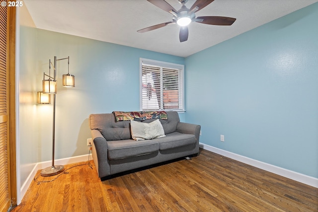 sitting room with baseboards, a ceiling fan, and wood finished floors
