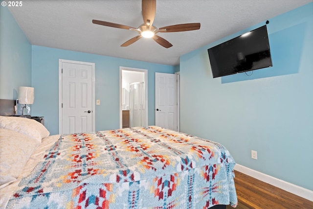 bedroom featuring baseboards, dark wood-type flooring, a textured ceiling, a ceiling fan, and ensuite bath