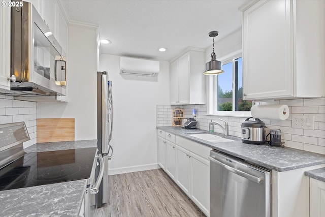 kitchen with backsplash, appliances with stainless steel finishes, a wall mounted AC, a sink, and white cabinets