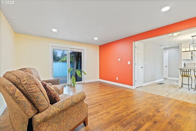 living room with light wood-type flooring, recessed lighting, and baseboards
