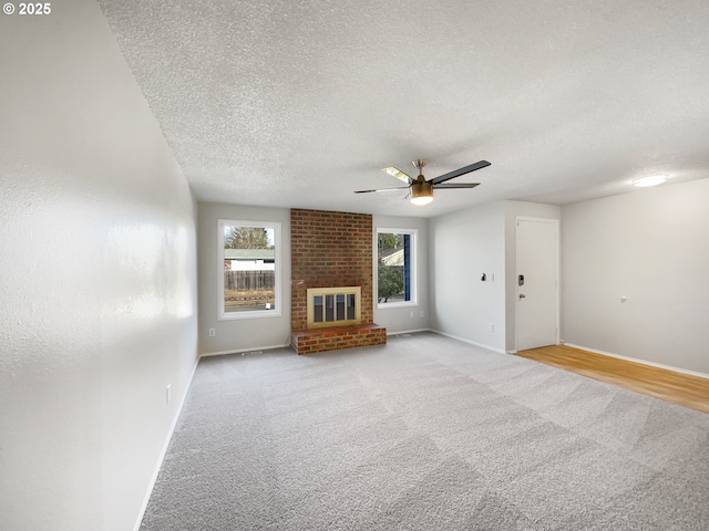 unfurnished living room with baseboards, light colored carpet, a brick fireplace, and a textured ceiling