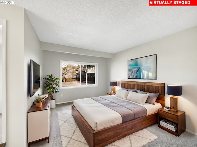 bedroom featuring a textured ceiling, baseboards, and light carpet