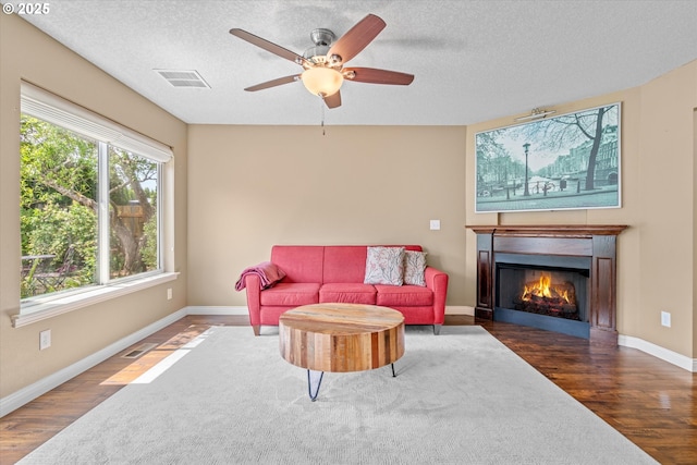 702 SW Burlingame Cir, Troutdale, OR 97060 - living room with wood finished floors, a glass covered fireplace, a textured ceiling, and a ceiling fan