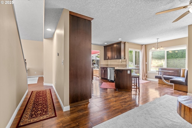 702 SW Burlingame Cir, Troutdale, OR 97060 - kitchen with stainless steel dishwasher, light countertops, a breakfast bar area, dark wood-type flooring, and a ceiling fan