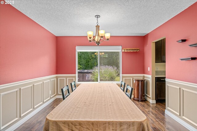 702 SW Burlingame Cir, Troutdale, OR 97060 - dining room featuring a chandelier, dark wood finished floors, a textured ceiling, wainscoting, and a decorative wall