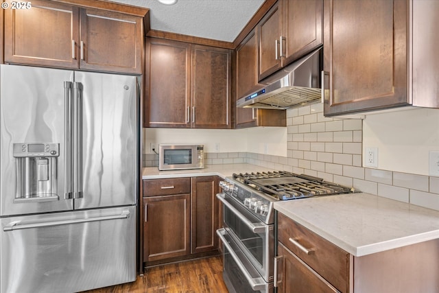702 SW Burlingame Cir, Troutdale, OR 97060 - kitchen with premium appliances, under cabinet range hood, dark wood-type flooring, light countertops, and tasteful backsplash