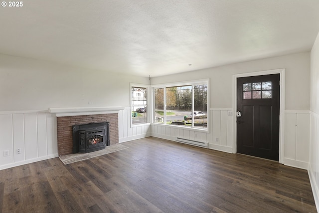 53112 NW Manor Dr, Scappoose, OR 97056 - unfurnished living room with a wood stove, a wainscoted wall, wood finished floors, and baseboard heating