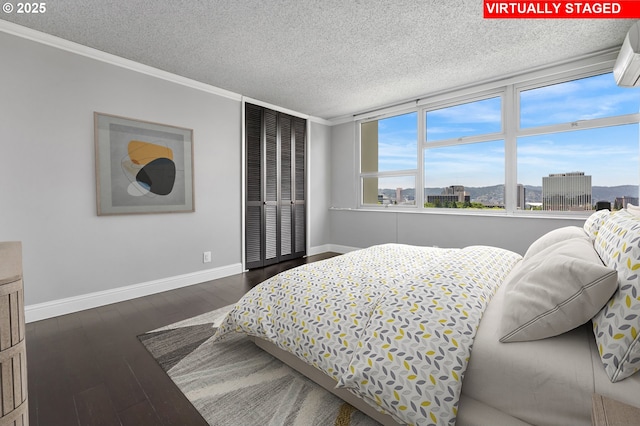 1220 NE 17th Ave Unit 12B, Portland, OR 97232 - bedroom featuring dark wood-type flooring, a textured ceiling, crown molding, and a wall unit AC