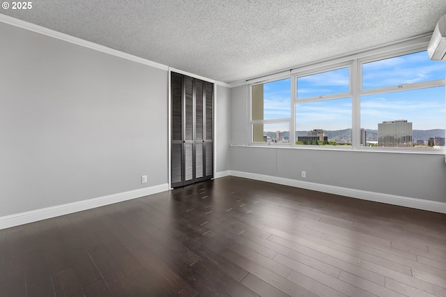 1220 NE 17th Ave Unit 12B, Portland, OR 97232 - spare room with a textured ceiling, dark wood finished floors, crown molding, and a wall mounted air conditioner