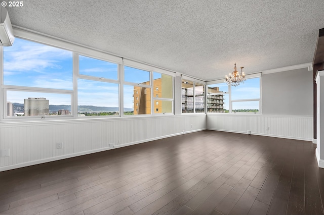 1220 NE 17th Ave Unit 12B, Portland, OR 97232 - unfurnished sunroom featuring a textured ceiling, a chandelier, wood finished floors, a wall mounted air conditioner, and a wainscoted wall