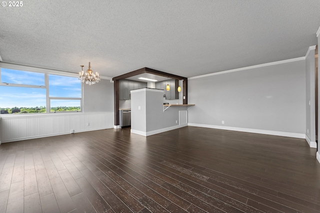 1220 NE 17th Ave Unit 12B, Portland, OR 97232 - unfurnished living room featuring a chandelier, a textured ceiling, ornamental molding, dark wood-style flooring, and a wainscoted wall