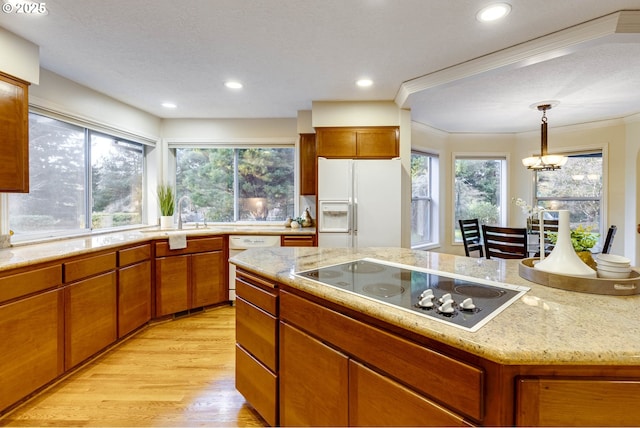 kitchen featuring sink, white appliances, light hardwood / wood-style flooring, decorative light fixtures, and a chandelier