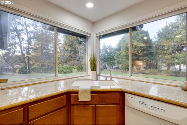 kitchen featuring sink, light stone counters, and white dishwasher