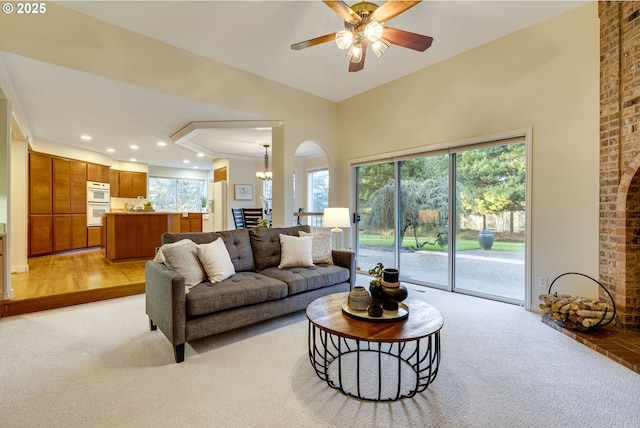 living room with a healthy amount of sunlight, ceiling fan with notable chandelier, and light carpet