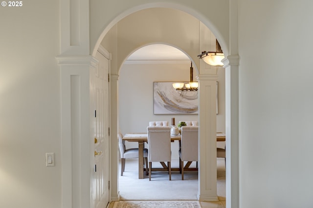 hallway with crown molding and a chandelier